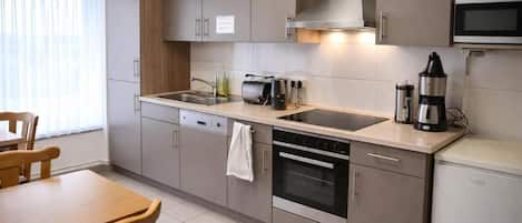 A compact kitchen with a double sink, a stove, and a microwave.