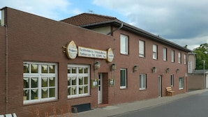 A brick building with a sign indicating a restaurant and a contact number.