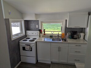 A compact kitchen with a stove, sink, and cabinets.