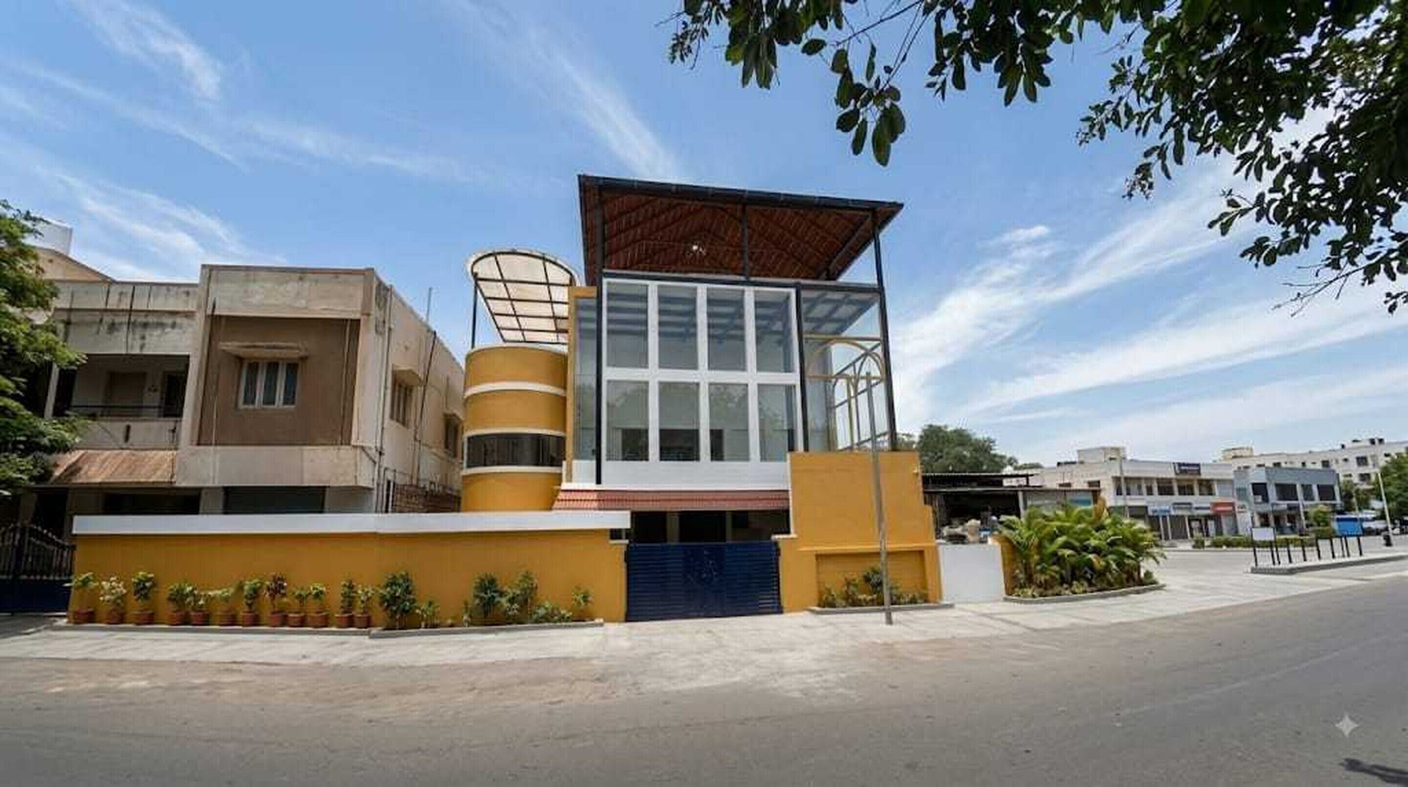 Un edificio moderno con fachada amarilla, entrada de vidrio y puerta azul.