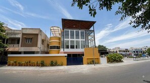 Un edificio moderno con fachada amarilla, entrada de vidrio y puerta azul.