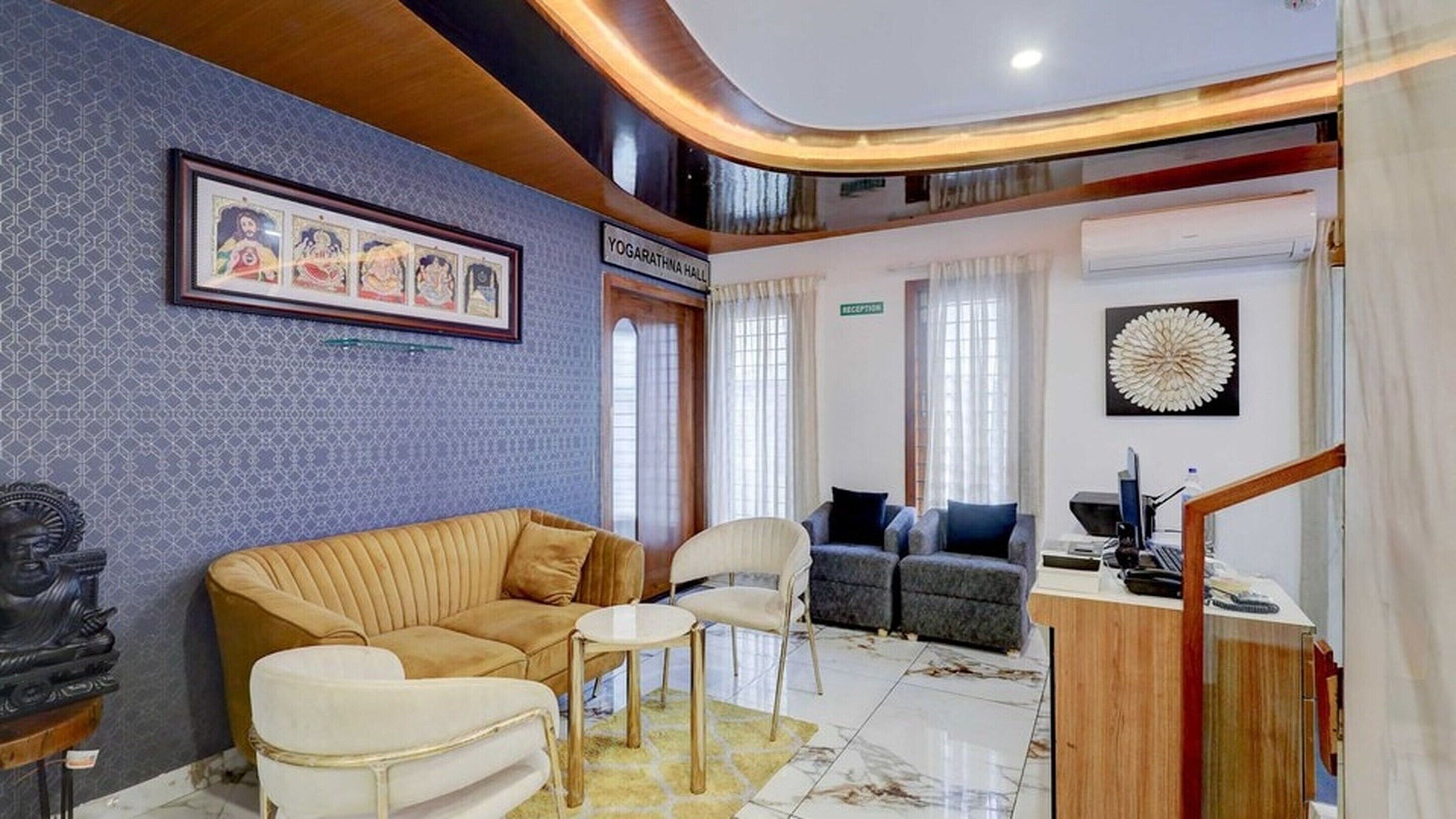 Un hall de hotel con mostrador de recepción, un sofá, sillas y una obra de arte enmarcada en la pared.