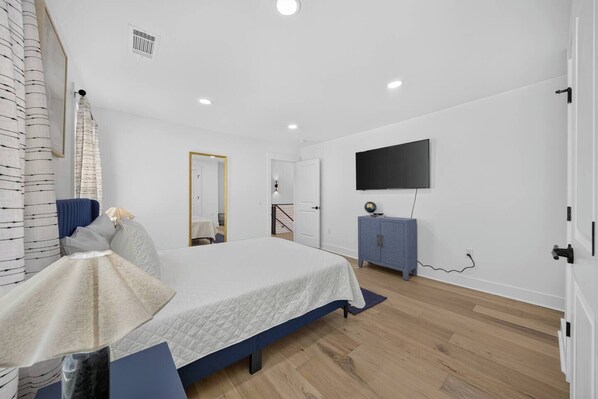 A bedroom with a bed, a dresser, a television, and a mirror.