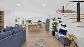 A modern living room with a sofa, a coffee table, and a staircase with a railing.