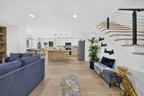 A modern living room with a sofa, a coffee table, and a staircase with a railing.