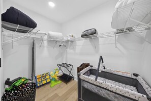A room with a crib, a changing table, and a storage shelf with folded clothes.