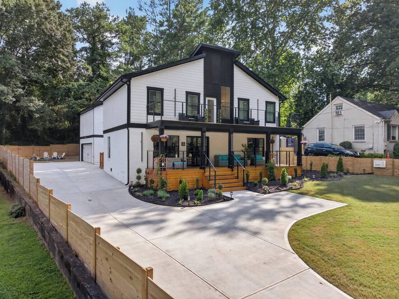 Een modern herenhuis met een overdekte veranda, een oprit en een omheinde achtertuin.