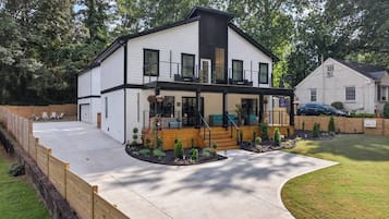 Een modern herenhuis met een overdekte veranda, een oprit en een omheinde achtertuin.