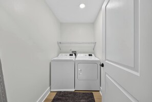 A laundry room with two front-loading washing machines and a drying rack.