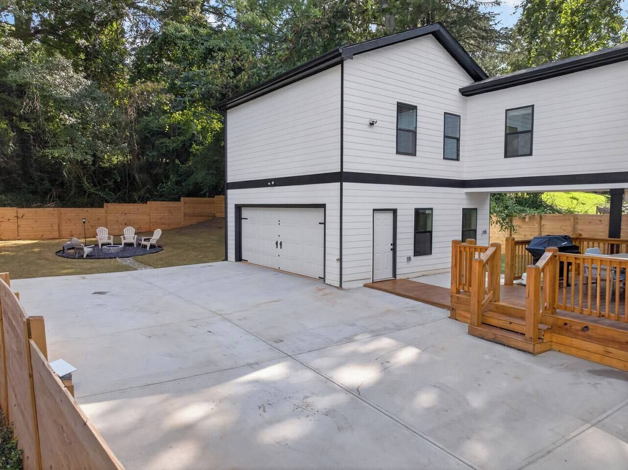A two-story house with a garage, a covered patio area, and a fenced yard with outdoor seating.