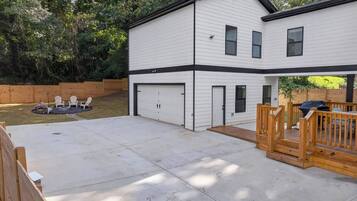A two-story house with a garage, a covered patio area, and a fenced yard with outdoor seating.