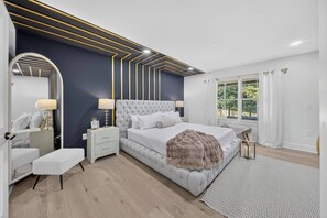 Una camera da letto moderna con un letto grande, comodini, uno specchio e vista sul verde.