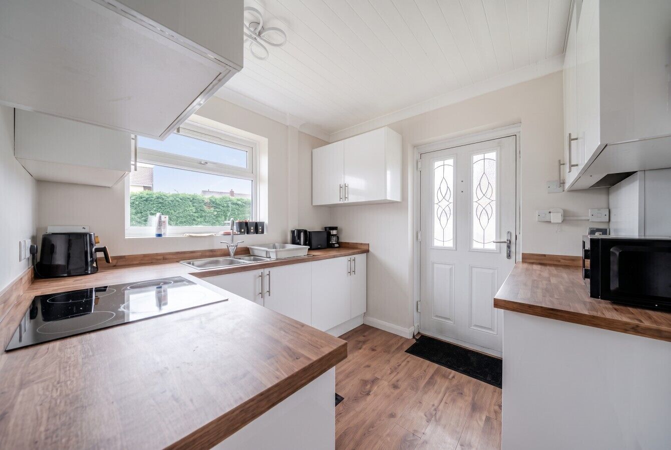 A modern kitchen with white cabinets, a wooden countertop, and a black stove.