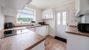 Una cocina moderna con armarios blancos, una encimera de madera y una estufa negra.