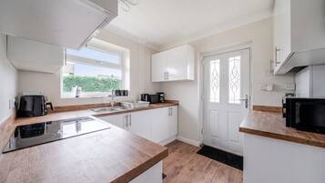 A modern kitchen with white cabinets, a wooden countertop, and a black stove.