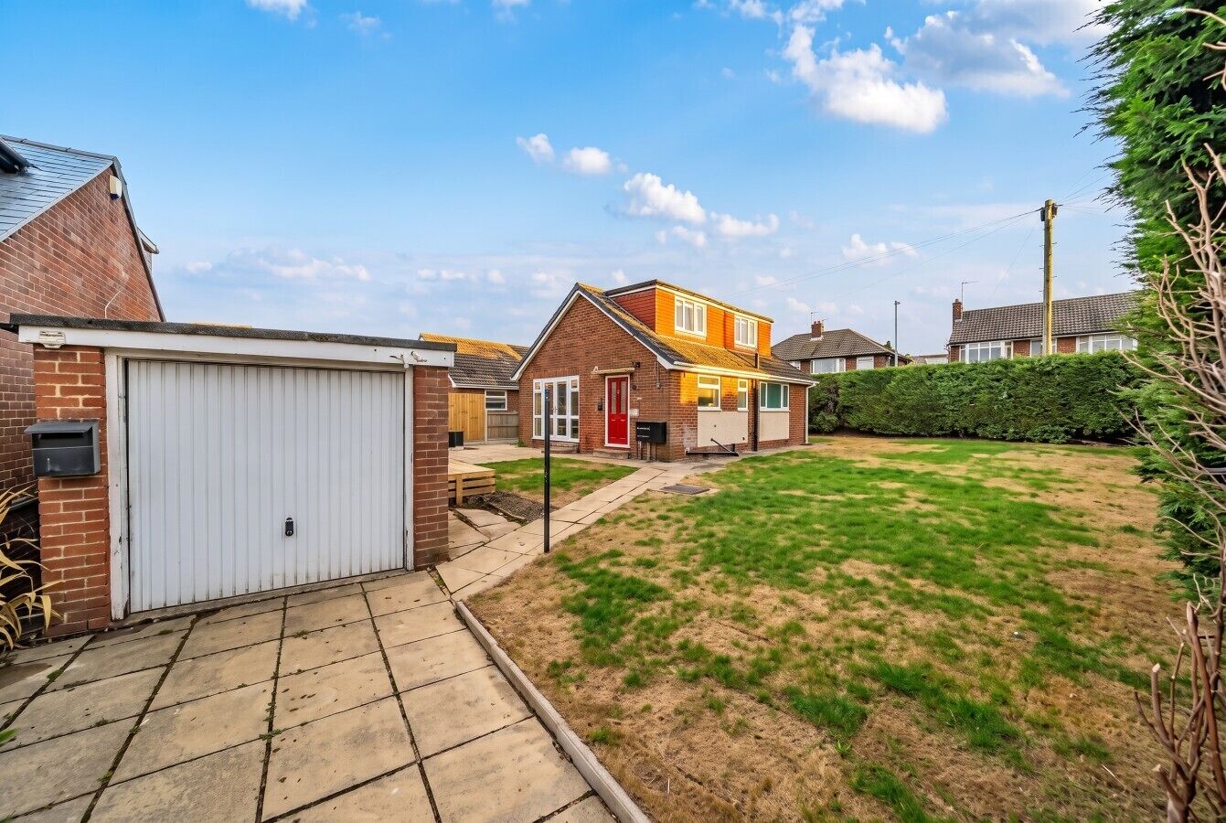 A residential area with a garage, a lawn, and houses with visible windows and doors.