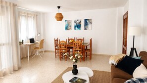 A living room with a dining area, a coffee table with a vase, a lamp, and artwork on the wall.
