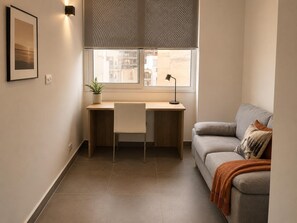 Una habitación con escritorio, silla y sofá.