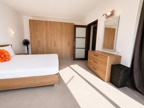 A bedroom with a bed, a dresser, a mirror, a fan, and a wardrobe. - Sliema 2BR Sea View Apartment Qui Si Sana with Terrace & BBQ (Sliema)