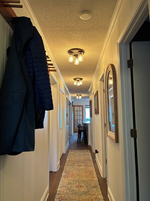 A hallway with a coat rack, a dining area with chairs and a table, and a door at the end. - The Summit at 4848-3 Bedrooms, Steps to the Snowshoe Village and Slopes! (Snowshoe)