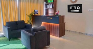 Zona de recepción de hotel con mostrador, un sofá y una pequeña mesa.