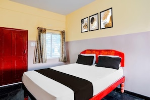 Una habitación de hotel con cama, ventana con cortinas, puerta y decoración en la pared.