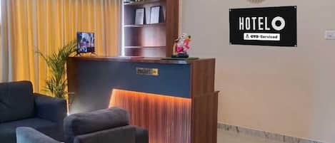 Un mostrador de recepción de hotel con un cartel que dice 'RECEPTION', una foto enmarcada y una estatua sobre el mostrador.