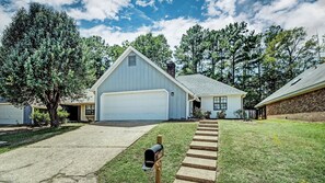 A residential house with a garage, a front yard with a mailbox, and a driveway leading to the garage.