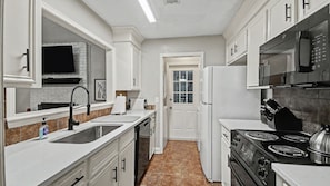 A kitchen with white cabinetry, a stainless steel sink, a built-in oven, and a refrigerator. - Peaceful Retreat Near the Reservoir (Ridgeland)