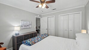 A bedroom with a bed, a dresser, a ceiling fan, and a door leading to a closet.