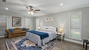 A bedroom with a bed, a nightstand, a lamp, a ceiling fan, a window with blinds, and a framed picture on the wall. - Peaceful Retreat Near the Reservoir (Ridgeland)