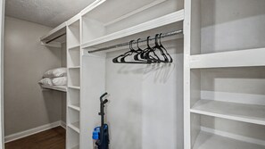 A walk-in closet with white shelving, a hanging rod, and a vacuum cleaner. - Peaceful Retreat Near the Reservoir (Ridgeland)