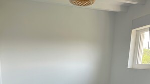 Een bed met een blauwgroene en witte spreideken, een nachtkastje en een lamp.