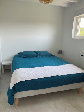 A bed with a teal and white bedspread, a bedside table, and a lamp. - Préchacq-les-Bains (Préchacq-les-Bains)