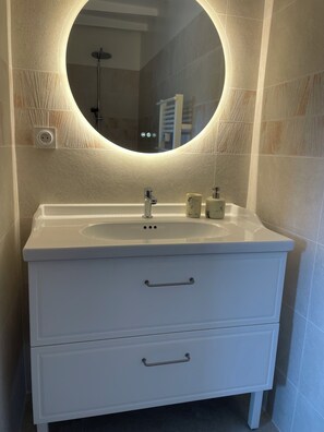 A bathroom with a white vanity, a round mirror, and a handheld showerhead. - Préchacq-les-Bains (Préchacq-les-Bains)