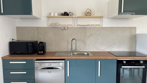 Een moderne keuken met een vaatwasser, oven, magnetron en koffiezetapparaat.