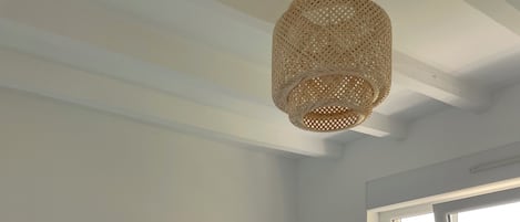 A bedroom with a bed, a window, and a hanging light fixture.