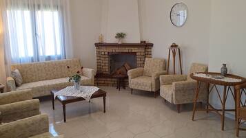 A living room with a fireplace, patterned sofas, a coffee table, and a clock on the wall.