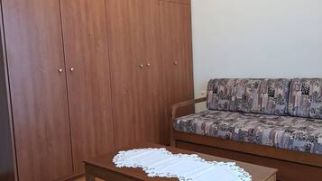 Una habitació amb un armari de fusta, un sofà estampat i una taula de centre de fusta amb un corredor de taula de renda.