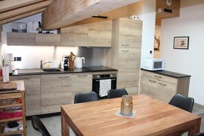 Eine moderne Küche mit Holzschränken, einem Esstisch und einer Mikrowelle.