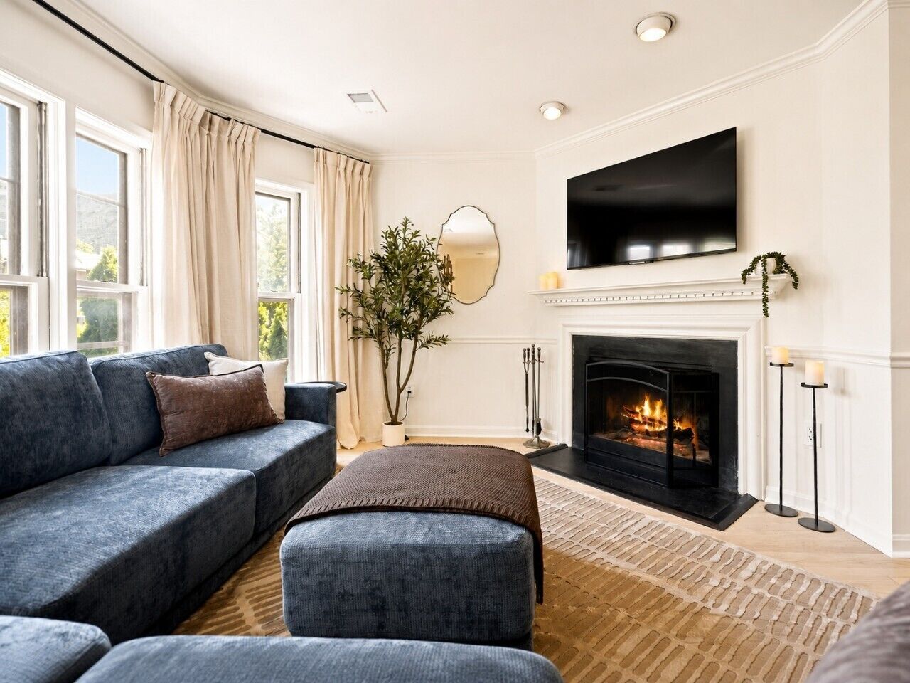 A living room with a fireplace, a sofa, a television, and a large window.