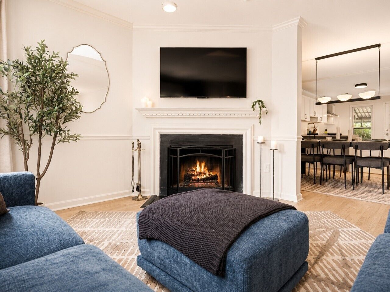 Een moderne woonkamer met een open haard, een flatscreen televisie en blauwe gestoffeerde meubels.