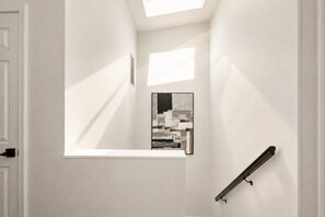 A hallway with a skylight, a framed artwork, and a handrail. - The Monroe by Willow · Mt Pleasant · 4BR Residence (Washington)