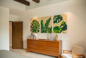 A room with a wooden cabinet, a chair, and three wall-mounted paintings of green leaves. - Lovely 2-bedroom condo with AC in vibrant Zona Romantica of Puerto Vallarta (Puerto Vallarta)