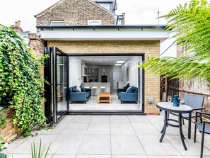 Una casa moderna con puerta de vidrio que da a una sala de estar con dos sofás y una mesa de centro.