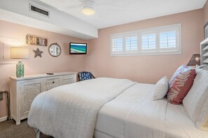 A bedroom with a bed, a dresser, a television, and a window. - The Islander 314 Dolphin Cove (Destin)
