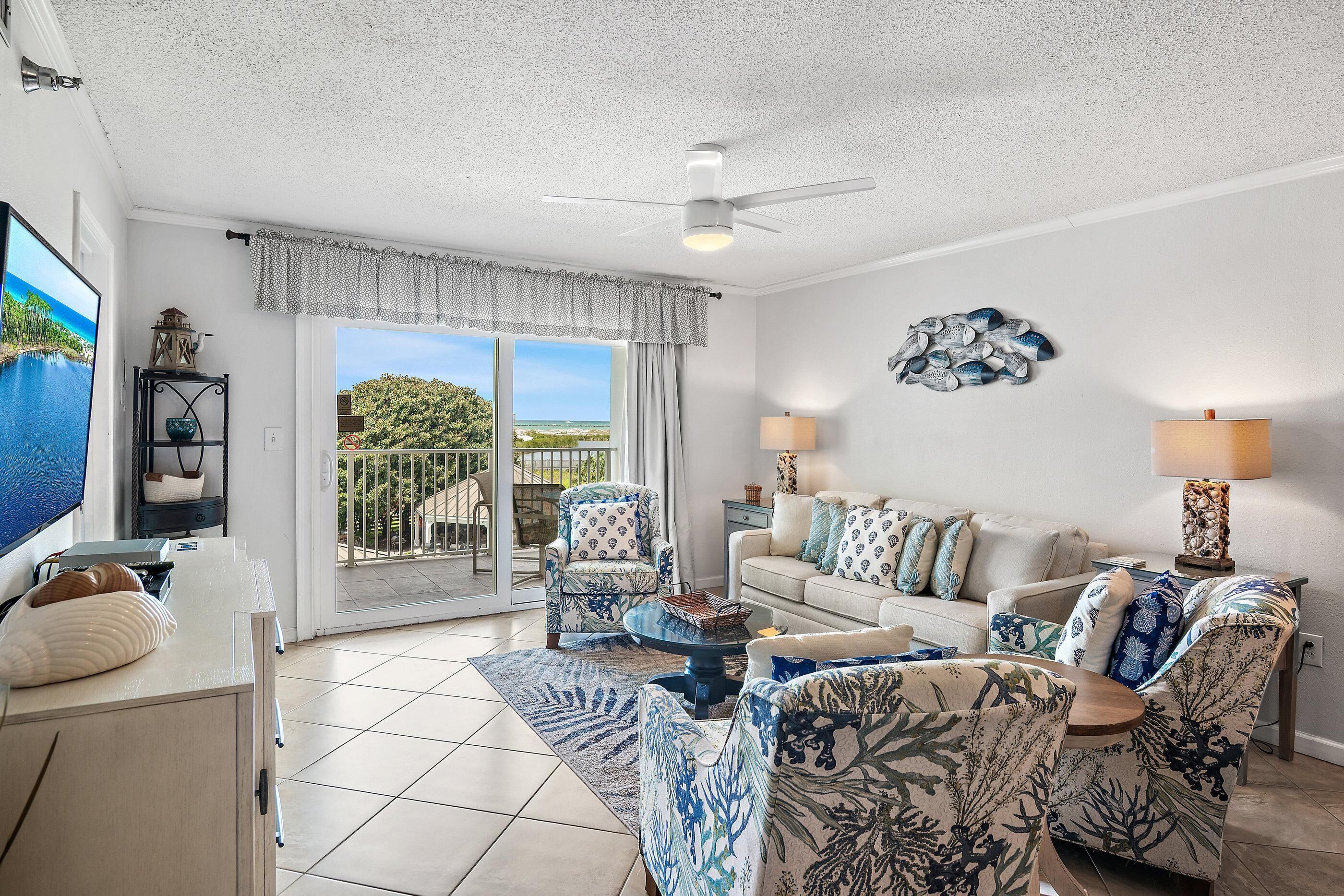 A spacious living room with a large window, a ceiling fan, and a view of the outdoors.