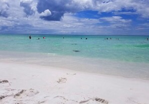 Een strand met helder turquoise water en wit zand.