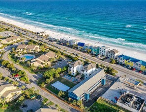 An aerial view of a coastal residential area with beachfront properties, a swimming pool, and a gas station. - Lakeview #9 - Paradise By The Gulf (Miramar Beach)