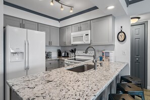 A modern kitchen with a granite countertop, stainless steel appliances, and a built-in microwave. - Lakeview #9 - Paradise By The Gulf (Miramar Beach)
